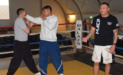 Air Force Staff Sgt. Dominic Buzzeli, 732nd Provost Marshal Office, throws a punch at his opponent, Sgt. James Barrett, 4th BCT, 1st Armd. Div., during Friday Night Fights on COB Adder, Jan 8. During the fights, COB Adder’s Memorial Hall was filled to capacity.