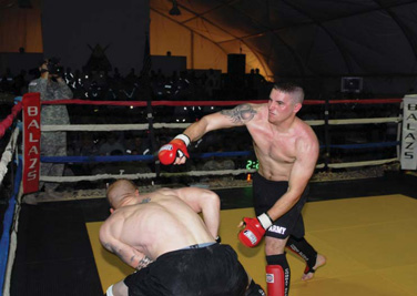 Air Force Staff Sgt. Dominic Buzzeli, 732nd Provost Marshal Office, throws a punch at his opponent, Sgt. James Barrett, 4th BCT, 1st Armd. Div., during Friday Night Fights on COB Adder, Jan 8. During the fights, COB Adder’s Memorial Hall was filled to capacity.